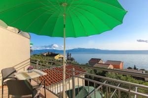 a green umbrella on a balcony with a view of the water at Apartments Villa Alex in Podaca