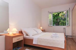 a white bedroom with a bed and a window at Apartments Villa Alex in Podaca