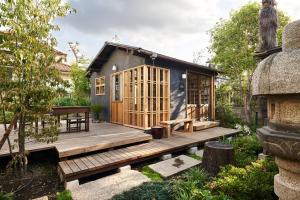 ein kleines Haus in einem Garten mit einer Holzterrasse in der Unterkunft ちゃぶだい Guesthouse,Cafe&Bar in Kawagoe