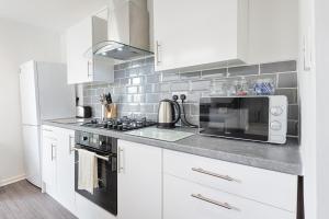 a kitchen with white cabinets and a microwave at Amazing views of the City in Swansea