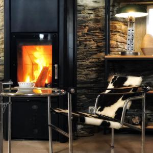 a room with a fireplace with a chair and a table at Les Rochers in Cerisy-la-Forêt