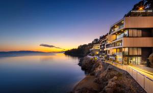 a building next to a body of water at night at Boutique & Design Hotel Navis - Small Luxury Hotels of the World in Opatija