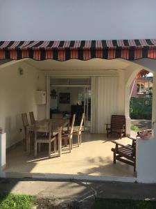 a patio with a table and chairs and a awning at Villa les Palmiers in Les Trois-Îlets