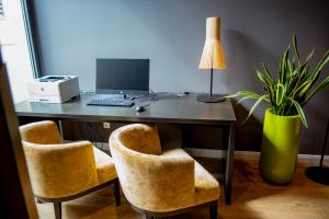 a desk with a computer and two chairs and a plant at Caravelle Hotel im Park in Bad Kreuznach