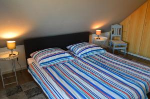ein Schlafzimmer mit einem Bett mit zwei Kissen und einem Stuhl in der Unterkunft Ferienhaus Heimathafen Neßmersiel in Neßmersiel