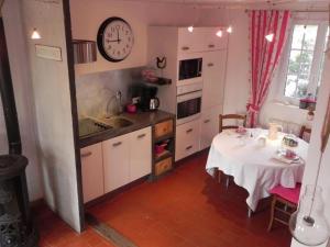 eine Küche mit einem Tisch und einer Uhr an der Wand in der Unterkunft Le Grand Gîte in Dorengt