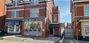 a brick building with a car parked in front of a store at The Grays in Blackpool