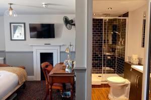 a bedroom with a desk and a bathroom with a shower at Admiral Hardy in London