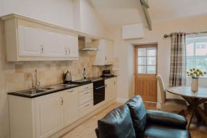 a kitchen with white cabinets and a table and a couch at Dunlin in Belford