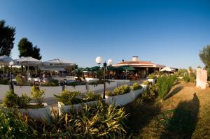 un jardin avec des plantes et des parasols dans un restaurant dans l'établissement Happy Camp mobile homes in Centro Vacanze Bi Village, à Fažana