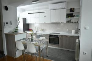 uma cozinha com armários brancos e uma mesa e cadeiras em Modern & Luxury em Skopje