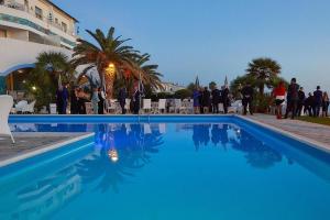 un grupo de personas de pie alrededor de una piscina en Hotel Poseidon, en Diamante