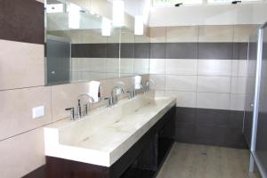 un bagno con tre lavandini e un grande specchio di Room2Board Hostel and Surf School a Jacó