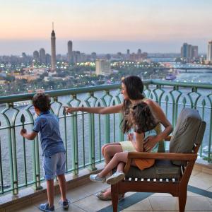 a woman and two children standing on a balcony at Four Seasons Hotel Cairo at Nile Plaza in Cairo