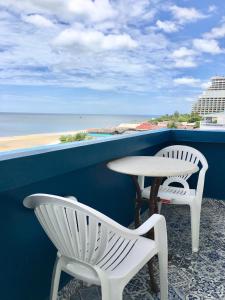 two white chairs and a table on a balcony with the beach at PierView Rooms in Hua Hin