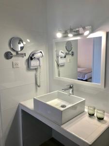 a white bathroom with a sink and a mirror at Hôtel Le Golfe Ecolabel EU in Porto Ota