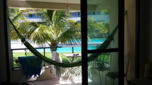 a hammock on a balcony with a view of a pool at Carneiros Beach Resort in Tamandaré