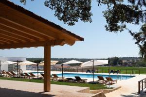 a swimming pool with lounge chairs and umbrellas at Casas Do Rio Sado - Sado River Country Retreat in Santa Margarida do Sado
