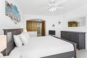 a bedroom with a white bed and a ceiling fan at Turtle's Nest Beach Resort in Meads Bay