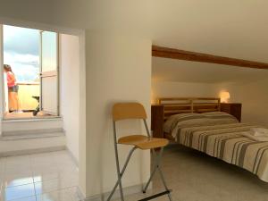 um quarto com uma cama, uma cadeira e uma janela em Gioberti 25 em Alghero