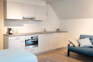 a kitchen with white cabinets and a blue couch at B&B Hof Beygaert in Aalst