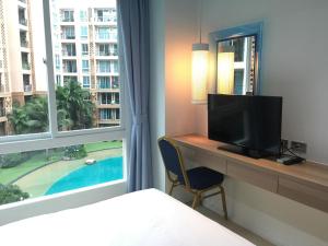 a bedroom with a desk with a television and a window at Atlantis Jomtien Waterworld Resort in Jomtien Beach