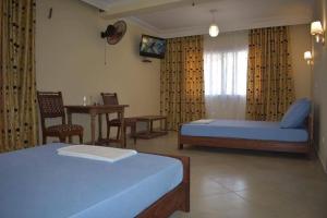 a hotel room with two beds and a table and a television at HOTEL MENABE in Morondava