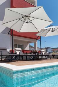 due tavoli e ombrelloni accanto a una piscina di Apartment House Ivan John a Podstrana