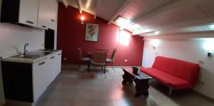 ein Wohnzimmer mit einem roten Sofa und einer Küche in der Unterkunft Residence La Palma in Catania