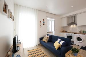 een woonkamer met een blauwe bank en een keuken bij Sea & Sun Apartment II in Nazaré