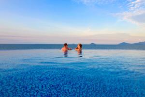two people standing in the water in the ocean at Fivitel Hoi An Hotel in Hoi An