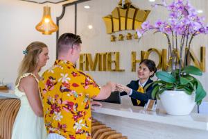 a man and a woman shaking hands at a counter at Fivitel Hoi An Hotel in Hoi An