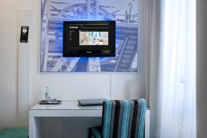 a room with a desk with a television on a wall at Hotel Ecu in Genk