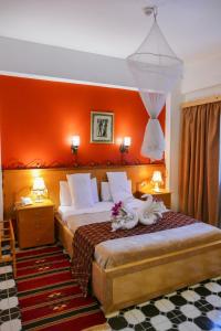 um quarto com uma cama com uma parede laranja em El Gezira Garden Hotel Luxor em Luxor