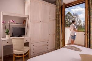 a man standing in a bedroom looking out the window at Tris Hotel in Orbetello