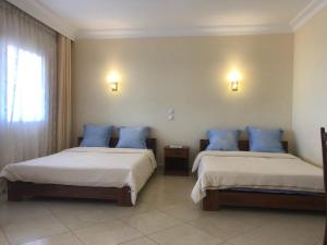 two beds in a hotel room with blue pillows at HOTEL MENABE in Morondava