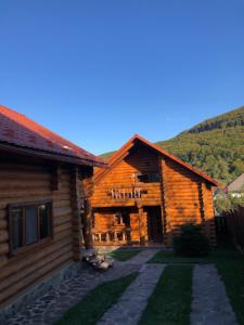 a log cabin with a pathway next to a house at Smerekovyi Dvir in Polyana