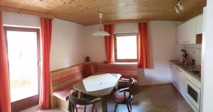 eine kleine Küche mit einem Tisch und 2 Fenstern in der Unterkunft Haus Bergblick in Prägraten