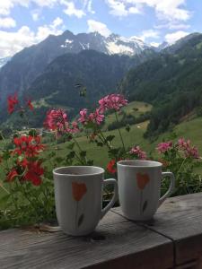 two coffee cups sitting on a wooden table with flowers at Haus Bergblick in Prägraten