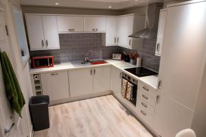 a small kitchen with white cabinets and a microwave at Sandy bottoms in Llandudno