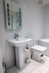 a white bathroom with a sink and a toilet at Sandy bottoms in Llandudno +22 photos