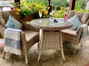 a glass table and chairs on a patio with flowers at The Claremont Hotel-Adult Only in Polperro