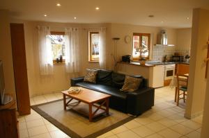 a living room with a black couch and a table at Ferienwohnung Am Erlenhof in Gleiszellen-Gleishorbach