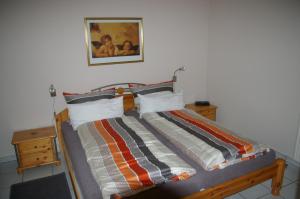 1 cama con edredón a rayas en un dormitorio en Ferienwohnung Am Erlenhof, en Gleiszellen-Gleishorbach