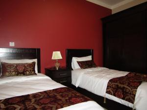two beds in a room with red walls at Petra Monastery Tourist Hotel in Wadi Musa +71 photos
