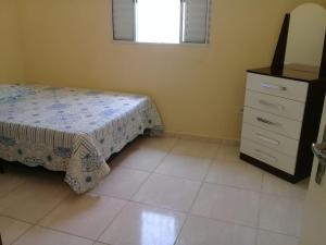 a bedroom with a bed and a dresser and a window at Linda casa ! in Mongaguá