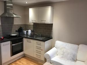 eine kleine Küche mit einem weißen Sofa und einem Waschbecken in der Unterkunft 1 Lisburne House in Aberystwyth