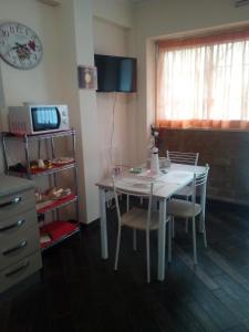 a kitchen with a white table and chairs and a microwave at Le Rose dell'Etna - Intero Appartamento in Trecastagni