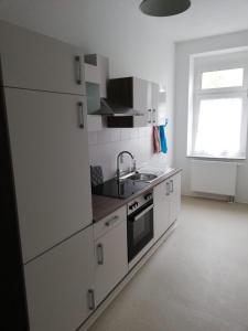 een witte keuken met een wastafel en een fornuis bij Ferienwohnung "OTTO" in Erfurt