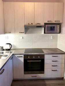 a kitchen with white cabinets and a stove top oven at Kings main square Apartment - AC - Balcony - Coffee Machine - Washer - Kitchen- Parking in Poprad